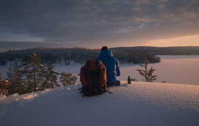 The hiker is resting on a snow-covered hillside in a stunningly beautiful place. dramatic light