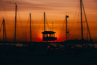Silhouette sailboats in marina at sunset