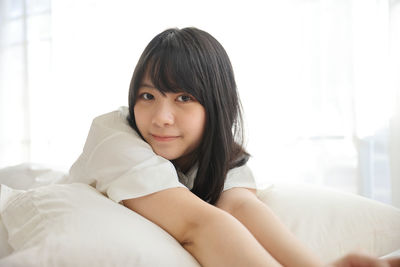 Portrait of young woman sitting on bed at home