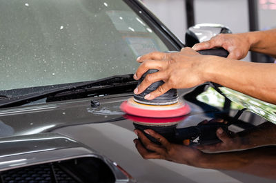 Cropped hands of man polishing car