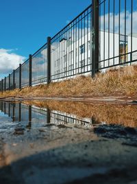 Fence by railing against sky