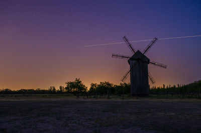 Traditional windmill on field against sky at sunset