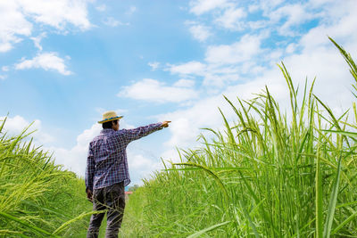 Rear view of woman standing on field against sky