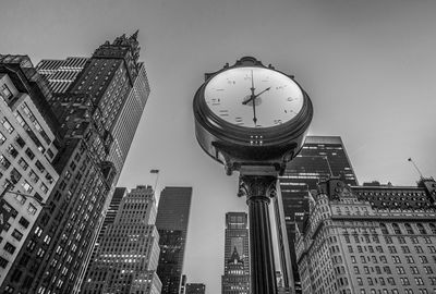 Low angle view of clock against tall buildings
