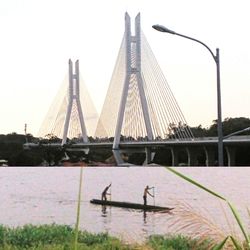 Suspension bridge in city against sky