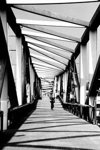 Rear view of man walking on bridge amidst buildings