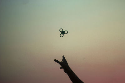 Low angle view of human hand is throwing up a spinner to the beautiful sky