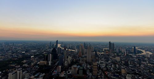 Aerial view of buildings in city against sky during sunset