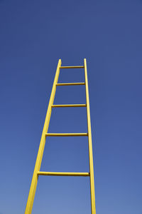 Yellow ladder by clear blue sky