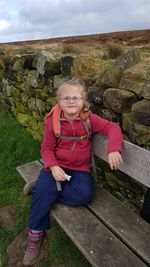 Full length of girl sitting on grass against sky