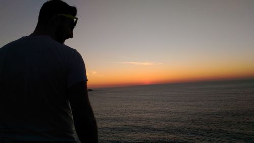 Silhouette man with camera against sky during sunset