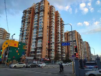 Vehicles on road by buildings against sky