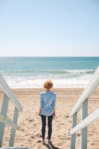 High angle view of mid adult woman standing by footpath at beach