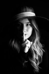 Portrait of young woman against black background