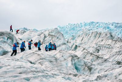 Group of people on snowcapped mountain against sky