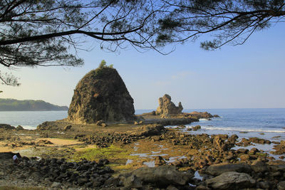 Rock formation on beach against sky