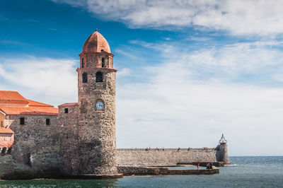 Tower by sea against sky