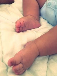 Low section of baby lying on bed