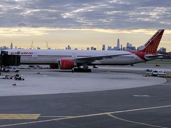 Airplane on airport runway against sky during sunset