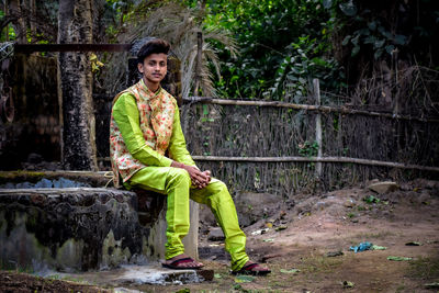 Full length of young man sitting outdoors