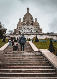 People at temple against cloudy sky