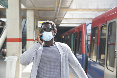 Portrait of man standing by train at railroad station