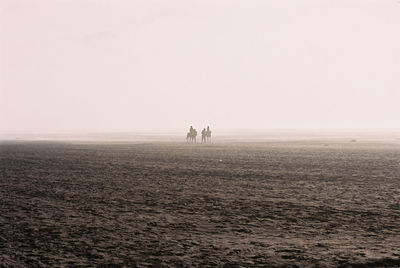 People on field in desert against sky