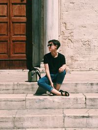 Full length of young woman sitting against wall
