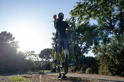 Young man standing on exercising equipment in park