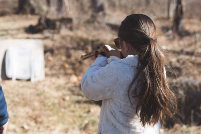 Rear view of woman aiming rifle