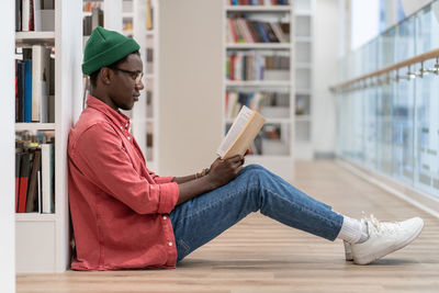 Concentrated african american student man with book spending free time in library, enjoying reading.