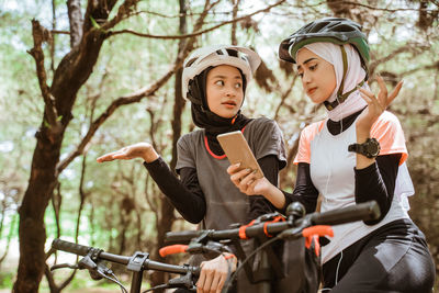 Female friends gesturing while holding mobile phone