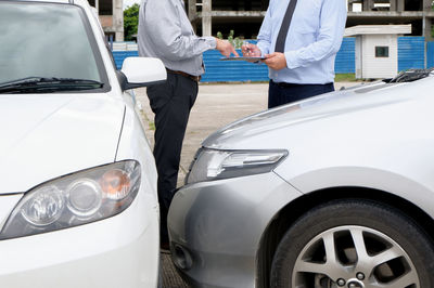 People standing by car on road