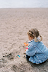 Rear view of girl playing with sand at beach