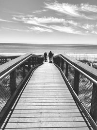 Boardwalk leading towards sea against sky