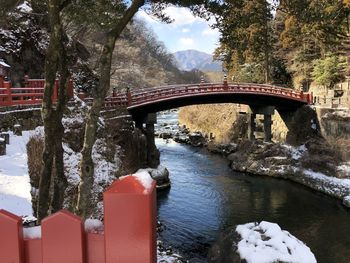 Arch bridge over river against trees