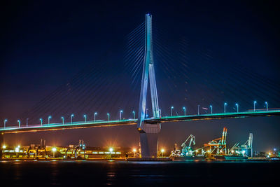 Illuminated bridge over river against sky at night