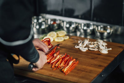 Cooking dinner - chef holding a knife and cutting red bell pepper