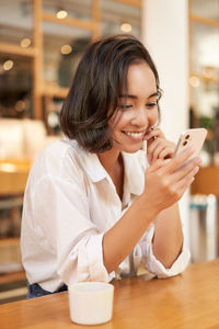 Young woman using mobile phone in cafe