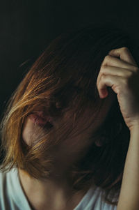 Close-up of woman with tousled hair against black background