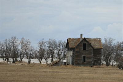 House on field by trees against sky