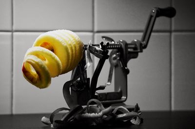 Close-up of apple on peeler in kitchen