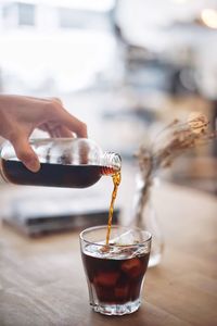 Cropped image of bartender pouring drink in glass at bar