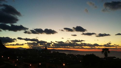 Silhouette trees and cityscape against sky during sunset