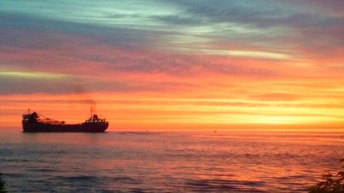 Boat sailing in sea at sunset