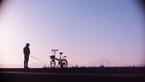 Silhouette man standing on field against sky during sunset