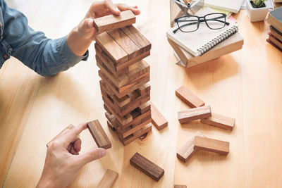 Cropped hands of colleagues stacking wooden blocks on desk