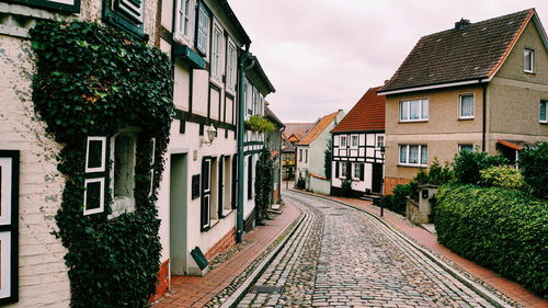 Footpath amidst houses and buildings against sky