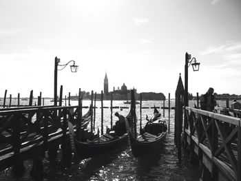 Traditional gondolas moored by jetties in grand canal against sky