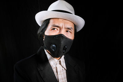 Portrait of man covering face against black background